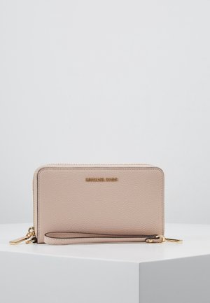 Beige leren polsportemonnee met ritssluiting rondom, voorzien van goudkleurige hardware en een afneembare band, geplaatst op een witte ondergrond.