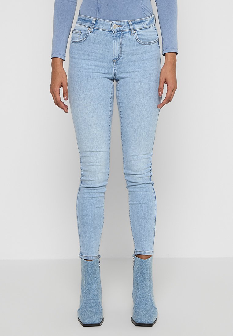 Helles blaue Skinny-Jeans aus Baumwollmix mit Verblendungen, Fünf-Taschen-Design und hoher Taille, kombiniert mit strukturierten blauen Knöchelstiefeln.