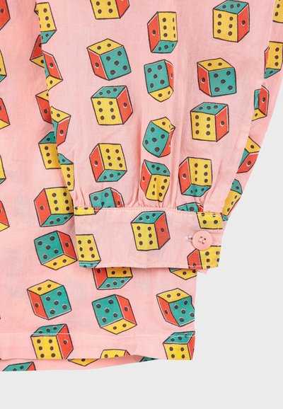 Patterned shirt featuring pink fabric with a dice print in yellow, green, and red. Includes buttoned cuff details and gathered hem.