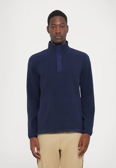 Pullover in pile blu navy con colletto alto, dotato di bottoni e maniche lunghe. Texture morbida, design casual.
