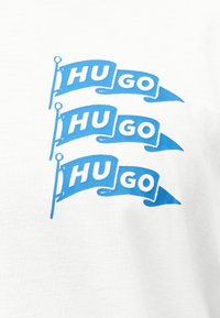 Τρία μπλε γραφικά σημαιών με λευκό κείμενο "HU GO" στοιβαγμένα κάθετα πάνω σε λευκό υφασμάτινο φόντο.