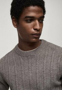 Gray knitted sweater with ribbed texture and round neckline. Fabric shows subtle vertical pattern and soft finish.