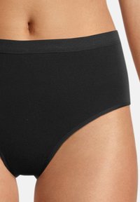 Schwarze hochgeschnittene Unterhose mit einer glatten, dehnbaren Textur und einem breiten elastischen Bund, der ein nahtloses Design für zusätzlichen Komfort bietet.