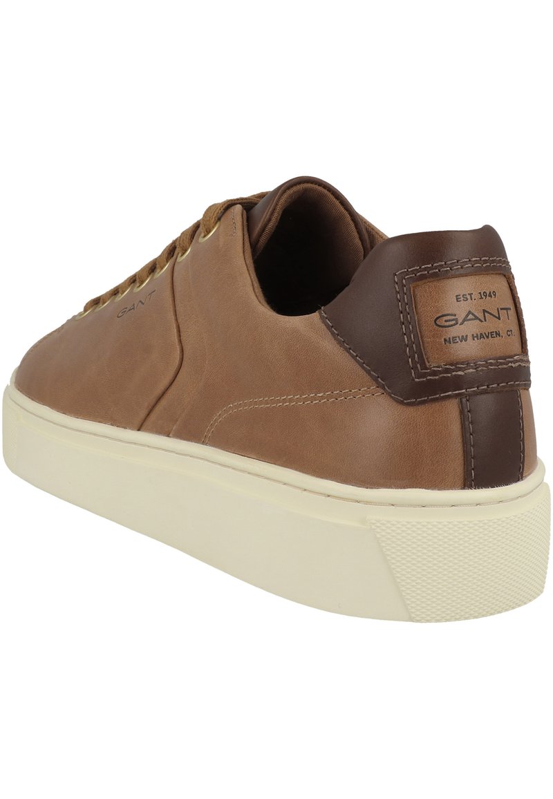 Zapatilla de cuero marrón con detalle texturizado en el talón, suela de goma color crema, y diseño de cordones con ojales dorados. Marca en el lateral.