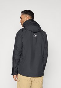 Svart vattentät jacka med huva, med en logga på baksidan. Lätt material, enkelt design och avslappnad passform.