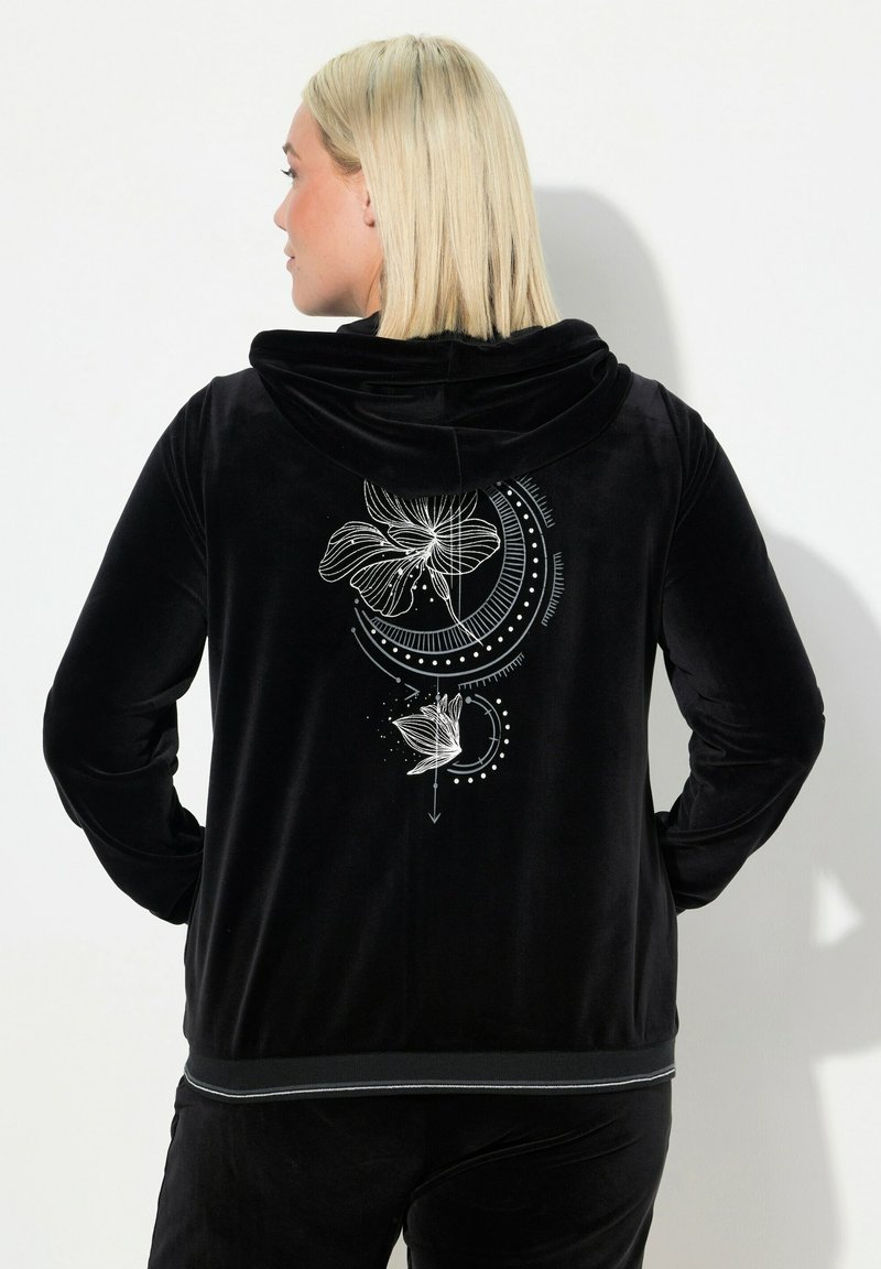 Chaqueta con capucha de terciopelo negro que presenta un dise�ño gráfico blanco de flores y patrones circulares en la parte trasera, con un ribete en contraste en el dobladillo.