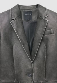 Blazer grigio in tessuto morbido, con rever a lancia, chiusura con un solo bottone e taschino sul petto. Etichetta con scritto "CALLIOPE", taglia S.