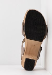 Sandale à semelle en bois avec semelle en caoutchouc noire, brides en suède beige, taille 37, photographiée par le dessous sur fond blanc.
