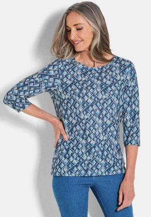 Blau gemusterte Bluse mit Dreiviertelärmeln, die ein geometrisches Design in verschiedenen Blau- und Weißtönen aufweist. Weicher Stoff.