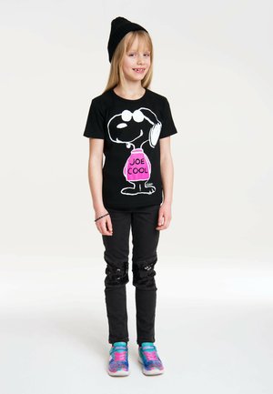 Black t-shirt with Snoopy graphic and "JOE COOL" in pink, paired with black jeans featuring sequin detail at knees and colorful sneakers.