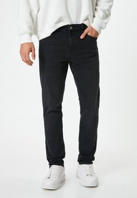 Jeans de mezclilla azul oscuro con un diseño ajustado, que presentan una textura sutil. Combinados con una sudadera blanca y zapatillas blancas.
