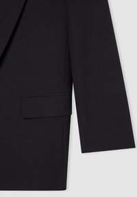 Blazer nero dal design su misura, tessuto liscio, revers aídos, una tasca sul petto e una silhouette strutturata con maniche dritte.