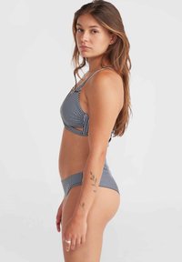 Completino bikini a righe navy e bianche con top bralette a spalline sottili e slip a vita bassa coordinati. Tessuto morbido e elastico con ritagli sul corpo.