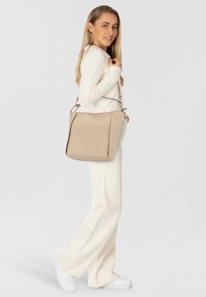 Beige Leder-Shopper mit einer strukturierten Form, ausgestattet mit einem oberen Griff und einem verstellbaren Schultergurt. Glatte Textur und dezentes Logo-Detail auf der Vorderseite.