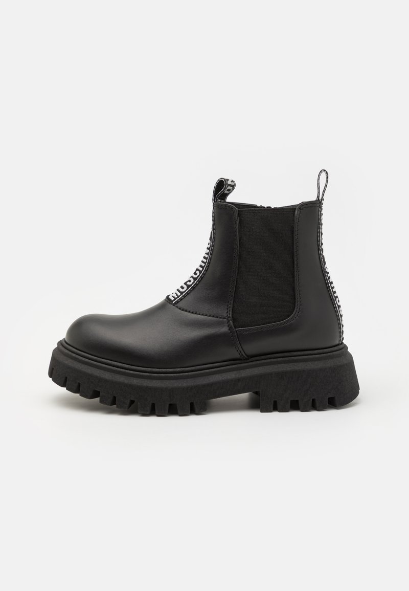 Botas Chelsea negras de cuero liso con suela de goma, paneles elásticos texturizados y lengüetas, con costuras en contraste.