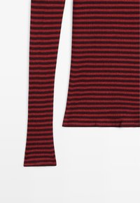 Red and dark red striped long-sleeve top with ribbed texture. Features fitted sleeves and a rounded neckline. Soft stretch material.