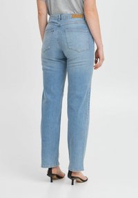 Hellblaue Jeans mit geradem Bein, mittelhoher Taille, braunem Lederlogo und minimaler Stichung an der Gesäßtasche.