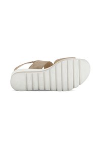Beige suède sandaal met een verstelbare band, voorzien van een witte rubberen zool met ribbels en een lichte hak voor grip en stabiliteit.