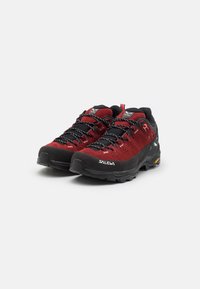 Chaussures de randonnée en suède rouge et en maille noire avec surface texturée, dotées de lacets noirs, d'un embout renforcé et d'accents de logo vifs.