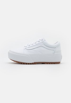Weißer Sneaker mit niedrigem Schaft, dicker Plateausohle und strukturierter brauner Außensohle, mit seitlichem Streifendetail und Schnürverschluss.