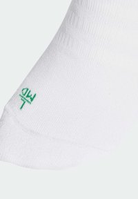 Vita strumpor i texturerat material med ett ribbat mönster. Har en liten grön logotyp nära tåområdet.