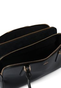 Μαύρη δερμάτινη τσάντα χειρός με χρυσά μεταλλικά στοιχεία, με κλείσιμο με φερμουάρ και τρεις ευρύχωρους χώρους με επένδυση μαύρου υφάσματος. Υφή με ανάγλυφη επιφάνεια.