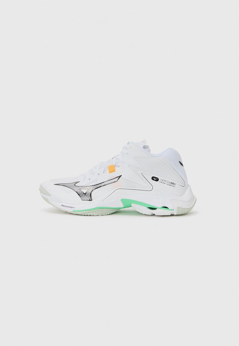 White athletic shoe with black and silver accents, green sole detail, textured overlays, and orange tab; curved design for support and flexibility.