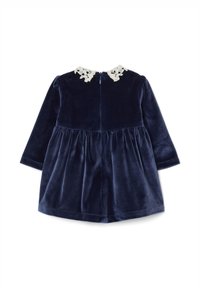 Vestido de bebé de terciopelo azul marino con mangas largas y cuello de encaje blanco, que presenta un cierre de cremallera en la parte posterior y una cintura fruncida.