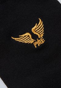 Sort sok med et gyldent broderet vingedesign og ordet "PMA". Materialet er blødt og tekstureret med strikmønster.