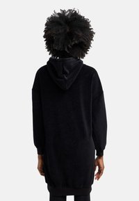 Schwarzes, oversized Kapuzenkleid aus weichem Stoff, mit langen Ärmeln, lockerer Passform und gerippten Bündchen an den Ärmeln und dem Saum.