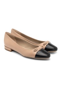 Ballerines en cuir beige avec bout noir, petit nœud sur le bout et petit talon carré. Texture lisse, forme arrondie.
