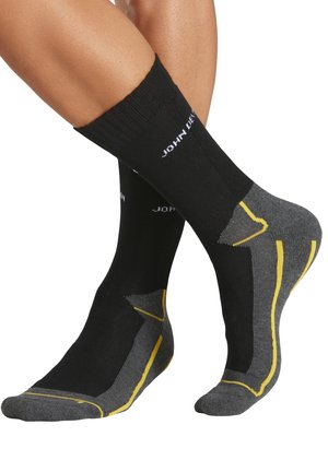 Schwarz-graue Socken mit gelben Akzenten, Rippbündchen, verstärkter Ferse und Spitze sowie Logodetail am oberen Bund.
