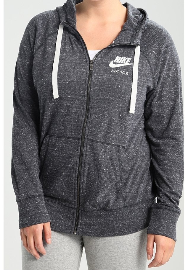 Šedá mikina na zip s bílými šňůrkami a logem Nike. Má dlouhé rukávy a dvě přední kapsy. Jemná textura s propleteným vzorem.