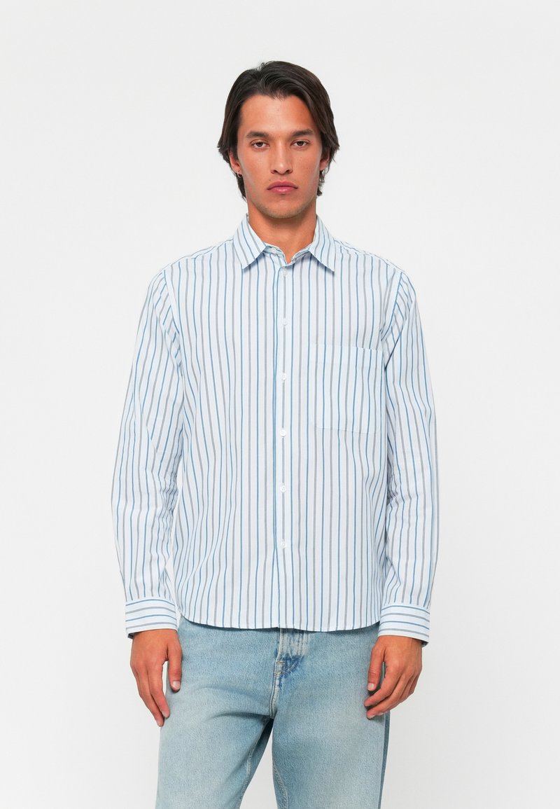 Long-sleeve button-up shirt in light blue with vertical white stripes, featuring a chest pocket and a classic collar. Soft fabric texture.
