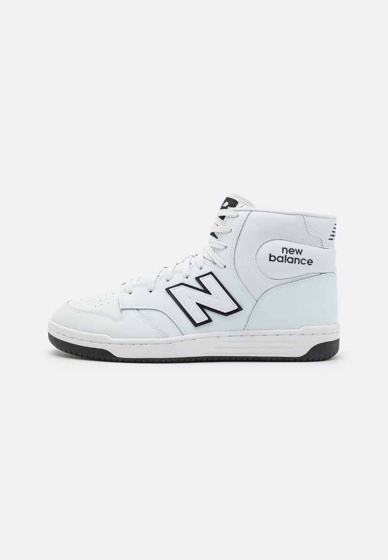 Biały sneakers typu high-top marki New Balance z czarnym logo i akcentami na podeszwie, pokazany z profilu na jednolitym jasnym tle.