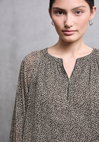 Bluse med leopardprint i gennemsigtigt stof, med rund halsudskæring og en kort lynlås, samlet detalje og et let, tekstureret udseende.