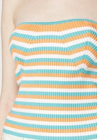 Top sin tirantes a rayas con textura acanalada en color naranja, teal y blanco. Presenta un diseño ajustado con un escote con banda.