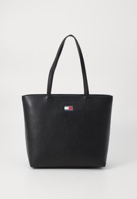 Schwarze Leder-Totetasche mit strukturierter Oberfläche, ausgestattet mit zwei Schulterriemen und einem kleinen Logo-Patch in Rot, Weiß und Blau auf der Vorderseite.