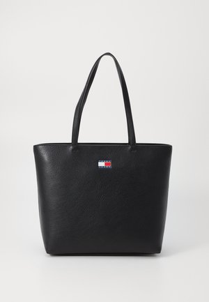Saco tote de couro preto com um acabamento texturizado, apresentando duas alças de ombro e um pequeno patch de logótipo em vermelho, branco e azul na parte da frente.