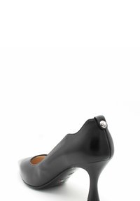 Chaussure à talon haut en cuir noir avec un bout pointu, des côtés découpés et un accent métallique sur le talon. Texture lisse avec une finition brillante.