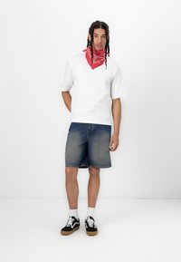 Hvit kortermet T-skjorte, blå denimshorts, rød bandana, svarte joggesko med hvite snører og gummisåler. Enkelt, uformelt antrekk.