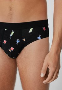 Slip di cotone nero con motivi colorati di cocktail e bevande. Vita elasticizzata, texture contrastanti, vestibilità aderente e superficie liscia.