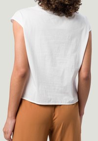 Top blanco de manga corta con un corte relajado y escote redondo. La tela parece suave con una textura sutil. El dobladillo tiene una ligera curva.