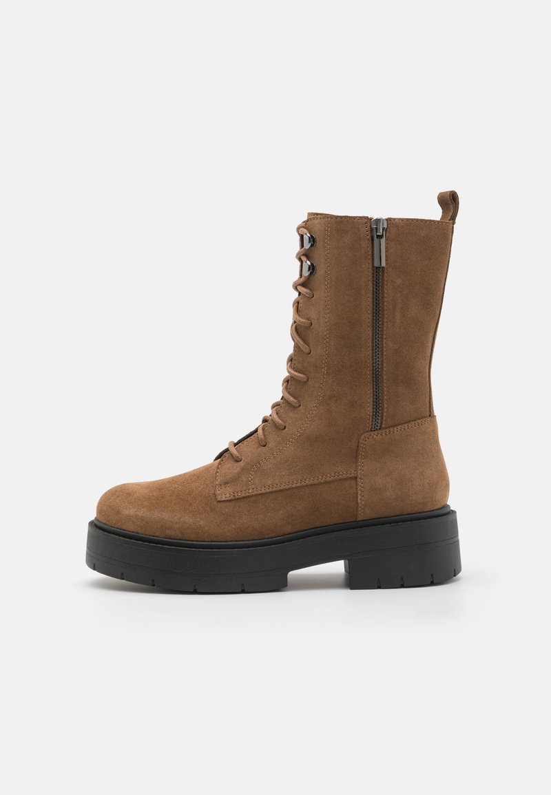 Bottines en daim marron à lacets avec fermeture éclair sur le côté, semelle noire épaisse et bout renforcé. Détails de couture sur les côtés.