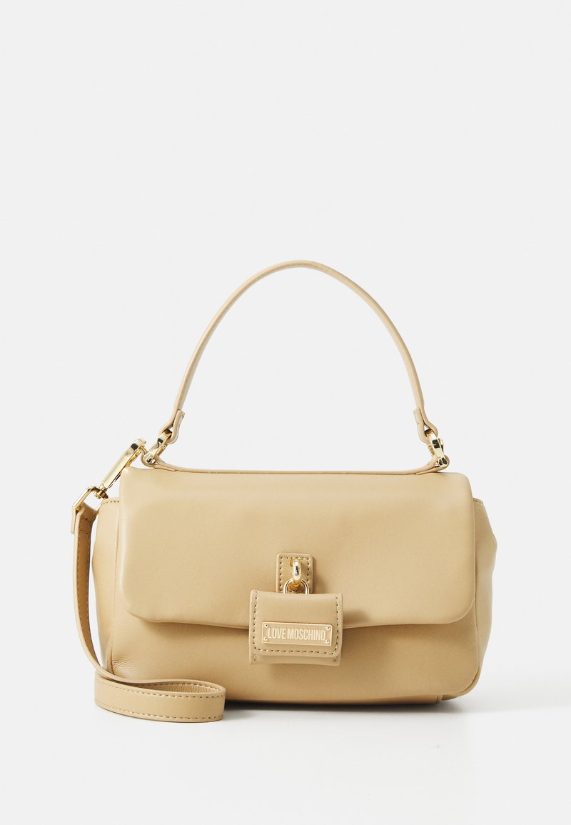 Beige faux leather handbag with a top handle, detachable shoulder strap, gold hardware, and a flap closure featuring a logo plaque.