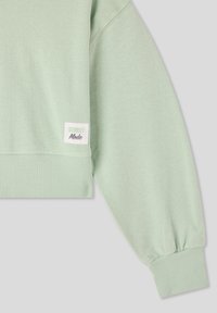 Felpa verde menta con orli e polsini a coste, con un'etichetta bianca che mostra "STREET Mode" sulla manica. Tessuto morbido e testurizzato.