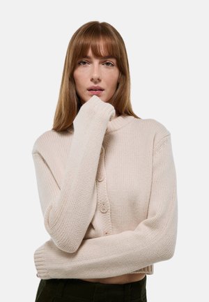 Cardigan en maille beige clair avec un col montant, comportant trois boutons, des poignets côtelés et une coupe décontractée. Le fil texturé ajoute de la profondeur.