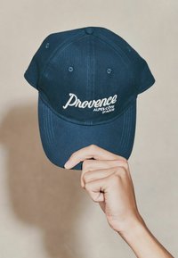 Căciulă de baseball bleu marin din țesătură, cu text alb brodat "Provence Alpes-Côte d'Azur" pe față, având un vârf curbat.