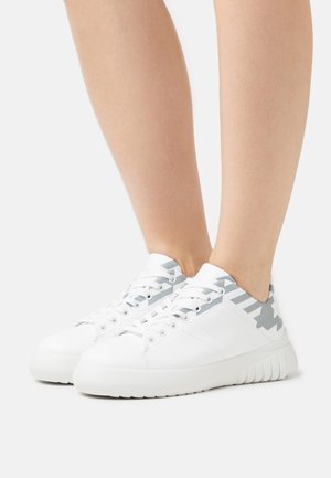 White sneaker with a smooth leather finish, featuring a light gray geometric pattern at the heel and a textured rubber sole.