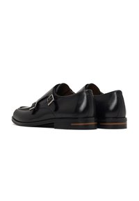 Zapatos de cuero negro con doble hebilla, un diseño elegante, punta redondeada y un tacón bajo con una franja de acento de madera.